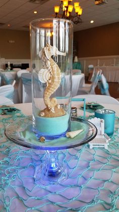 there is a glass vase with a seahorse in it on top of a table