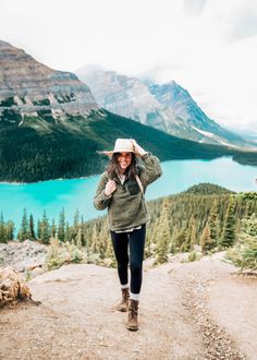 a woman standing on top of a mountain next to a lake