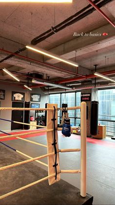 an empty boxing ring with two punching gloves hanging from the ropes