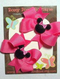 three minnie mouse hair clips with pink bows and butterflies on it's back side