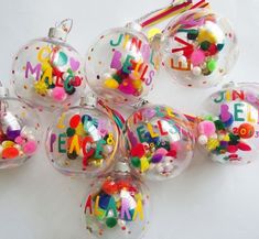 a group of glass christmas ornaments with letters and confetti on them, all decorated in different colors