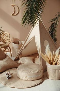 pillows and cushions are arranged on the floor in front of a palm tree, potted plant, and wicker chairs