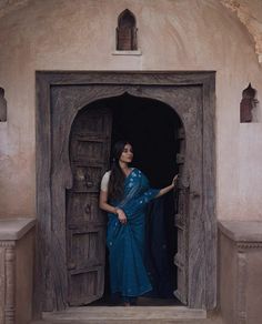 a woman in a blue sari standing at an open door