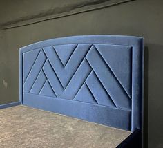 a blue headboard on top of a bed in a room with concrete floors and walls