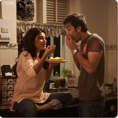 a man and woman are eating food in the kitchen while looking at each other's eyes