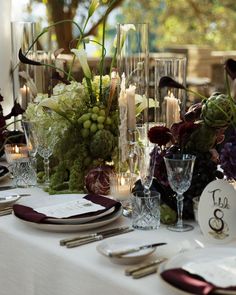 the table is set with candles, flowers and wine glasses for an elegant wedding reception