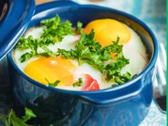 two eggs are in a blue bowl with parsley