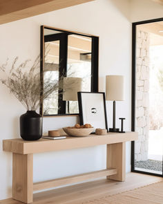 a wooden table topped with a bowl of fruit next to a mirror