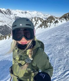 a woman in ski gear standing on top of a snow covered slope