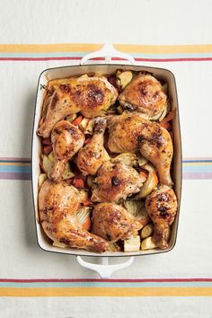 a casserole dish with chicken and vegetables on a striped tablecloth, top view