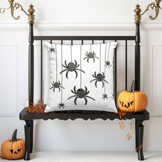 a black iron bed with two pumpkins on it and a spider pillow in the middle