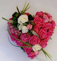 a heart - shaped arrangement of pink and white roses