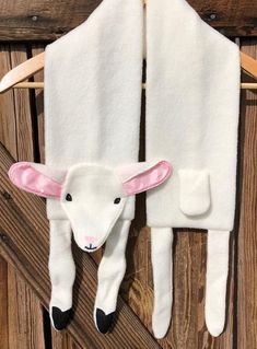 a white sheep is hanging on a clothes rack with pink ears and nose, as if it were made out of felt