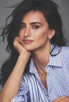 a woman with long hair wearing a blue and white striped shirt is posing for the camera