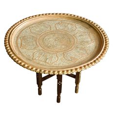 an ornately decorated gold tray sits on a wooden stand with two legs and feet