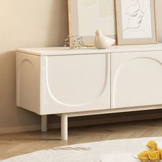 a white cabinet with two framed pictures on it next to a bowl of yellow rubber ducks