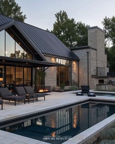 a house with a swimming pool in front of it and two lounge chairs next to the pool