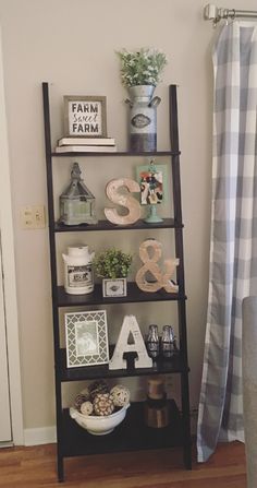 a shelf with letters and pictures on it in front of a shower curtain next to a window