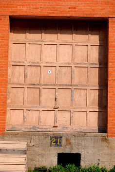 a fire hydrant sitting in front of a wooden garage door on the side of a brick building