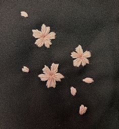 some pink flowers on a black cloth with white dots and petals in the middle,