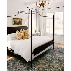 a bedroom with a four post bed and chandelier