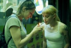 two women standing next to each other in front of a mirror holding a lit candle