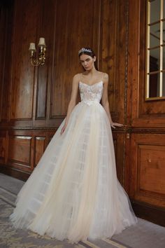 a woman standing in front of a wooden wall wearing a wedding dress