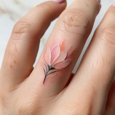 a woman's hand with a pink flower tattoo on her left thumb and finger