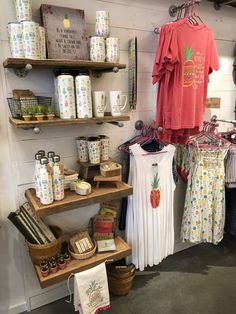 clothing and other items are on display in a store with wooden shelvings, baskets, and mugs