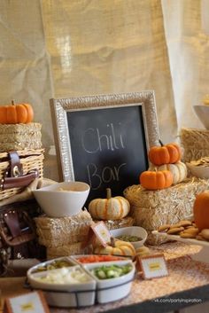 a table topped with hay bales filled with different types of foods and vegetables next to a chalkboard sign