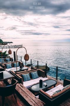 an outdoor seating area overlooking the ocean on a cloudy day