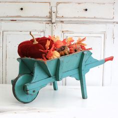 a wheelbarrow filled with pumpkins and gourds sits on a table