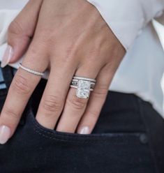 a woman's hand with a ring on top of her pants, holding onto the pocket of her jeans