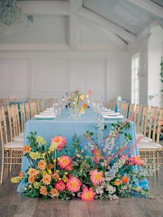 the table is set with blue linens and colorful flowers