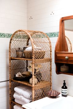 a bathroom with white tile walls and brown wooden shelves filled with towels, toiletries and other items