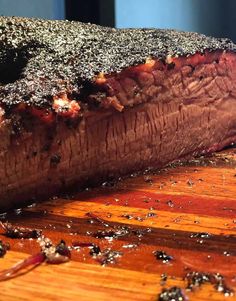 a piece of steak on a wooden cutting board with pepper sprinkled over it