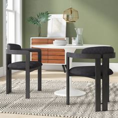 two chairs sitting on top of a rug in front of a white table and dresser