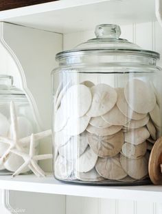 a glass jar filled with lots of buttons on top of a shelf