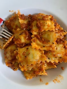 a white plate topped with lasagna covered in cheese and sauce next to a fork