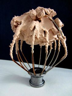 a whisk that is sitting on top of a metal stand with chocolate whipped cream in it