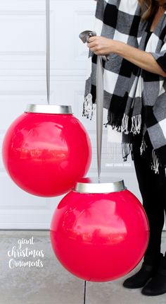 a woman standing next to two red vases on top of a cement floor with a black and white checkered scarf