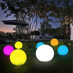 several different colored lights in the grass near trees