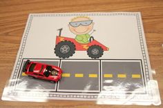 a red toy truck driving down a road next to a cut out of a car