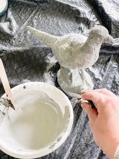 someone is painting a bird statue with white paint