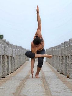 a man doing a handstand in the middle of a walkway with stone pillars