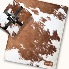 two brown and white cowhides with a black cross on the front one is folded