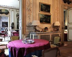 a dining room with chairs and a table covered in a pink tablecloth next to a fireplace