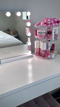 a white vanity with pink flowers on it and a mirror above it that has the lights turned on