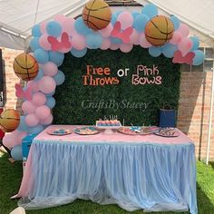 a table with balloons and basketballs on it at a pink and blue birthday party