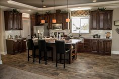 a kitchen with wooden floors and dark brown cabinetry is shown in this image, there are four bar stools at the center of the island